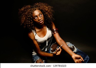 A young beautiful african american female poses as a track whore shooting up narcotics in this dark photo shoot against black
