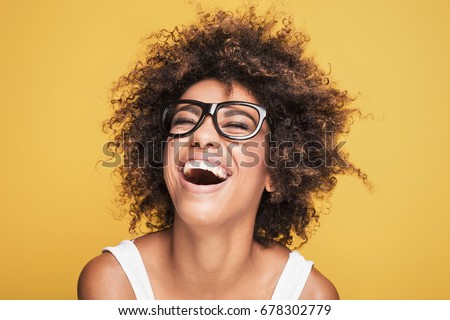Young beautiful african american girl with an afro hairstyle. Attractive girl wearing eyeglasses. Portrait. Yellow background. 