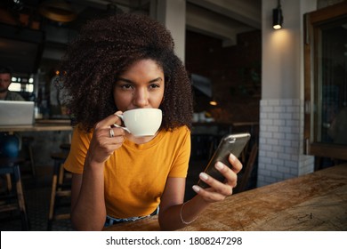 Young and beautiful African American woman sipping coffee in fashionable coffee shop. - Powered by Shutterstock