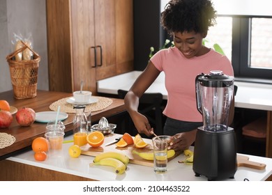 Young beautiful African American woman preparing healthy fruit juice for breakfast at home before workout - Powered by Shutterstock