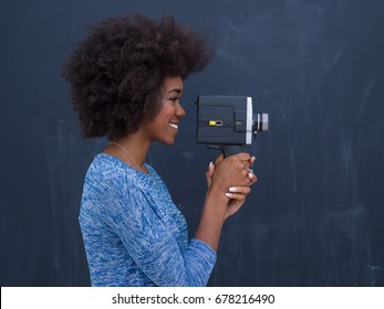 A Young Beautiful African American Woman Using A Retro Video Camera Isolated On A Gray Background