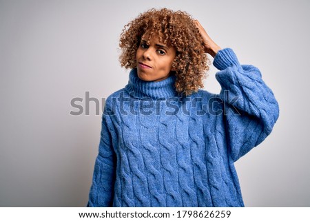Young beautiful african american woman wearing turtleneck sweater over white background confuse and wondering about question. Uncertain with doubt, thinking with hand on head. Pensive concept.