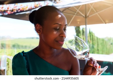 Young Beautiful African Ethnicity Woman Smiling And Drinking White Wine In Vineyard During Sunny Day Outside