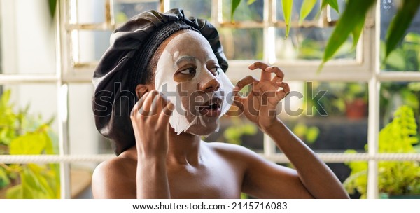 Young beautiful African woman in a cleansing face\
mask, skin care