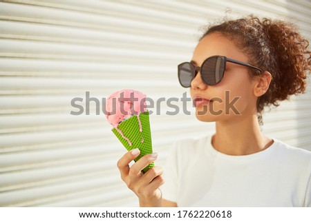 a young beautiful African-American girl in a white t-shirt and light jeans eats ice cream on a Sunny day. selective focusing. small focus area.