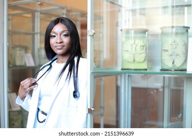 Young beautiful African-American medical student girl in white coat with stethoscope and in laboratory with human organs. Candid portrait. Future of health care. African Surgeon Concept