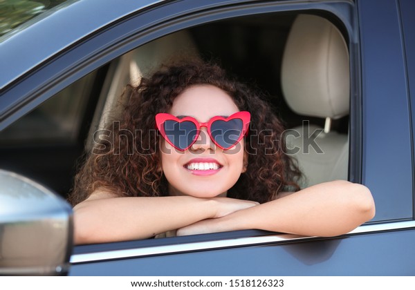 Young beautiful African-American woman wearing heart\
shaped glasses in car