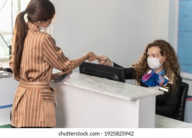 Young Beautiful Airline Company Staff Wearing Face Mask During Work With Colleagues And Tourist Customer For Prevent Covid-19 Infection During Coronavirus Pandemic. New Normal Traveling Concept.