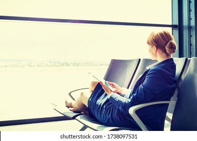 Young Beautiful Airport Staff Using Digital Tablet While Sitting On Chair During Break