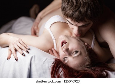 Young Beautiful Amorous Couple Making Love In Bed On White Background