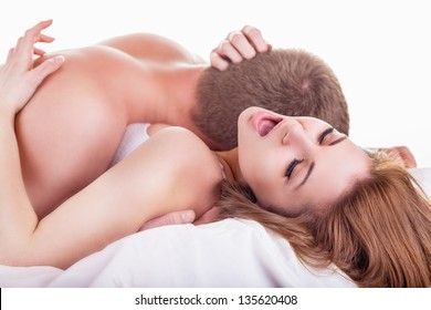 Young beautiful amorous couple making love in bed on white background