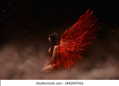 Young beautiful angel woman with red wings sits on a cloud. Night dark sky background with stars and space. Sexy latex dress. Valentine's Day concept. Goddess girl watching the universe from cosmos