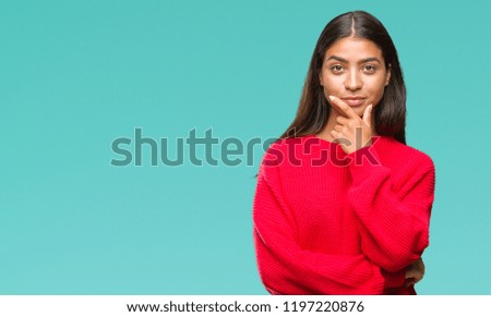 Young beautiful arab woman wearing winter sweater over isolated background looking confident at the camera with smile with crossed arms and hand raised on chin. Thinking positive.