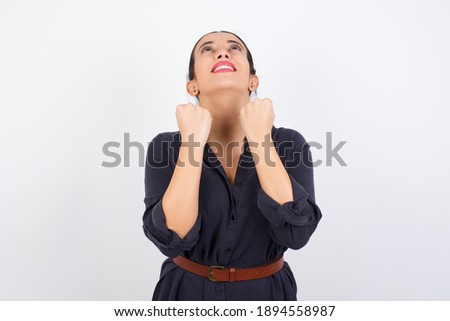 young beautiful Arab woman wearing gray dress against white studio background having success being glad to achieve his goals. Victory and triumph concept.