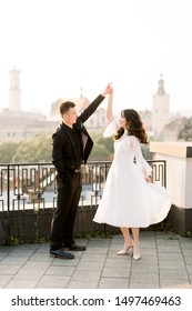 Young Beautiful Asian Bride And Groom On The Wedding Day Walking And Dancing On The Rooftop Of Old City. Ancient City Buildings Panorama.