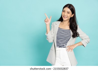 Young beautiful Asian business woman pointing to empty copy space isolated on green background - Shutterstock ID 2155032837
