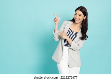 Young beautiful Asian business woman pointing to empty copy space isolated on green background