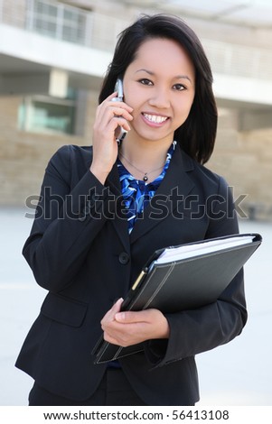 A young, beautiful asian business woman at office on phone