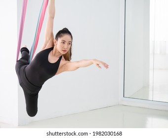 Young Beautiful Asian Dancer Dressed In Black Color Performing Aerial Dance With Multi-color Fabrics In The Studio.