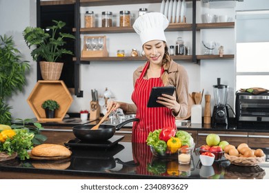 Young beautiful asian female chef cooking breakfast salad in the kitchen. Happy asian woman preparing healthy food with ingredient. Chef in uniform in the kitchen. - Powered by Shutterstock