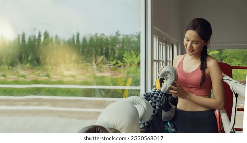 Young beautiful Asian female professional trainer training boxing in the gym checks the quality of boxing gloves suitable for training by choosing the best gloves to reduce and prevent injuries. - Powered by Shutterstock