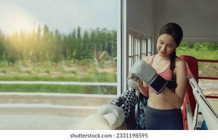 Young beautiful Asian female professional trainer training boxing in the gym checks the quality of boxing gloves suitable for training by choosing the best gloves to reduce and prevent injuries. - Powered by Shutterstock