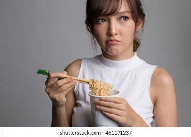 Young Beautiful Asian Girl Eating Instant Noodle Using Chopsticks.