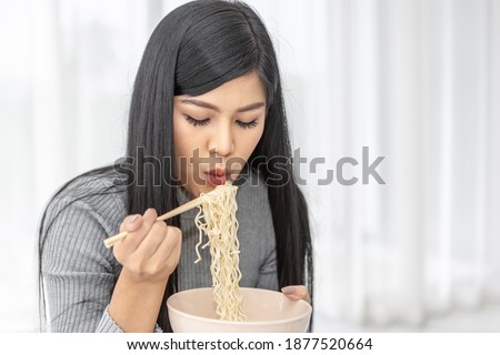 Young beautiful Asian girl using chopsticks to  eating yummy instant noodle