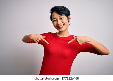Young beautiful asian girl wearing casual red t-shirt standing over isolated white background looking confident with smile on face, pointing oneself with fingers proud and happy.