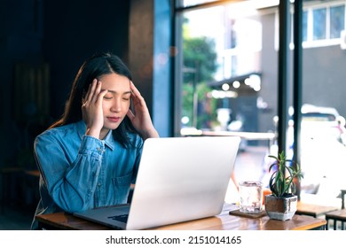 A Young Beautiful Asian Hipster Woman Serious Work On A Laptop At The Coffee Shop. A Female Entrepreneur Sitting Alone At A Table, Working Online While Social Distancing. Generation Z Business Ideas.