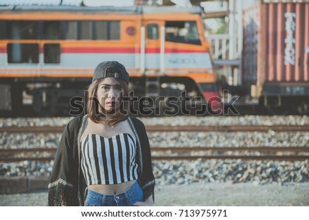 Young beautiful asian hipsters girl wear blackhat pose for take a picture on the railway in the evening vintage style