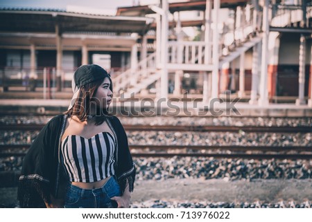Young beautiful asian hipsters girl wear blackhat pose for take a picture on the railway in the evening vintage style