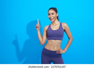 Young Beautiful Asian Sportswoman Doing Sport Wearing Sportswear Over Blue Background. Healthy And Fit Strong Female Concept.