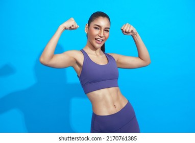 Young Beautiful Asian Sportswoman Doing Sport Wearing Sportswear Over Blue Background. Healthy And Fit Strong Female Concept.