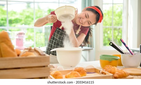 A young beautiful Asian woman is baking in her kitchen  , bakery and coffee shop business  - Shutterstock ID 2033416115