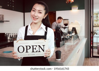 Young Beautiful Asian Woman Barista Holding Open Sign Broad At Restaurant And Coffee Shop For Telling Customers That Shop Is Ready To Service.