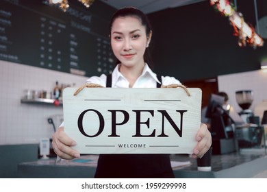 Young Beautiful Asian Woman Barista Holding Open Sign Broad At Restaurant And Coffee Shop For Telling Customers That Shop Is Ready To Service.