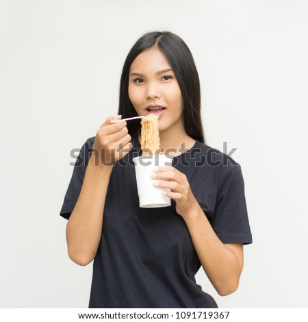 Young beautiful asian woman eating yummy hot and spicy instant noodle using chopsticks isolated on gray background.Unhealthy concept