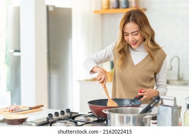 Young Beautiful Asian Woman Enjoy Cooking Healthy Food Fried Pasta On Cooking Pan In The Kitchen At Home. Happy Female Having Dinner Party Meeting Celebration With Friends On Holiday Vacation