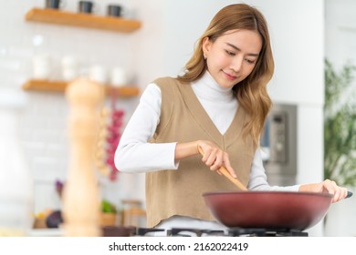 Young Beautiful Asian Woman Enjoy Cooking Healthy Food Fried Pasta On Cooking Pan In The Kitchen At Home. Happy Female Having Dinner Party Meeting Celebration With Friends On Holiday Vacation