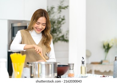 Young Beautiful Asian Woman Enjoy Cooking Healthy Food Fried Pasta On Cooking Pan In The Kitchen At Home. Happy Female Having Dinner Party Meeting Celebration With Friends On Holiday Vacation