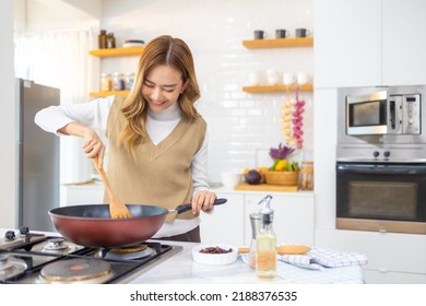 Young Beautiful Asian Woman Enjoy Cooking Healthy Food And Pasta In Cooking Pan On Stove In The Kitchen At Home. Happy Female Having Dinner Meeting Party Celebration With Friends On Holiday Vacation.