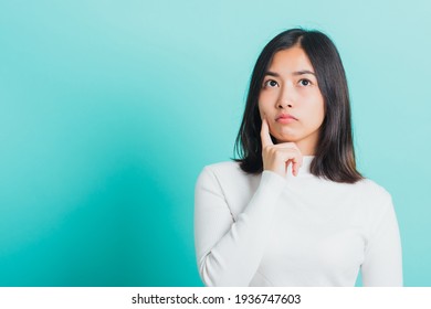 Young beautiful Asian woman hand near the face and thinking, Portrait  female touch chin dream dreamy having doubts, studio shot isolated on a blue background