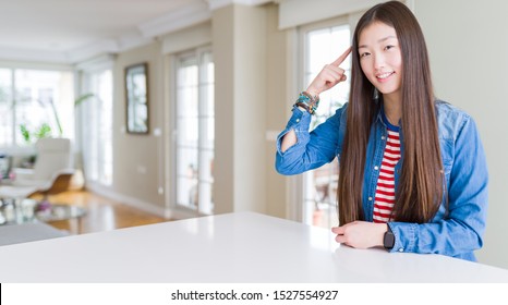 Young Beautiful Asian Woman With Long Hair Wearing Denim Jacket Smiling Pointing To Head With One Finger, Great Idea Or Thought, Good Memory