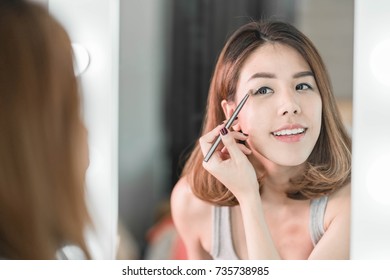 Young Beautiful Asian Woman making make-up near mirror - vintage effect filter
