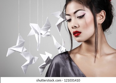 Young beautiful asian woman with origami paper pigeons, studio shot