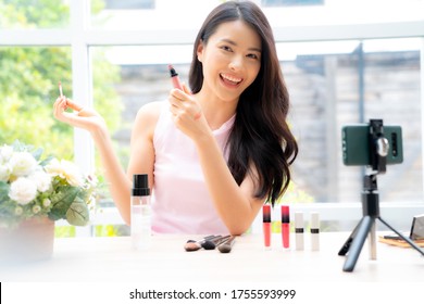 Young and  beautiful Asian woman performing live broadcast via smartphone teaching how to do make-up.