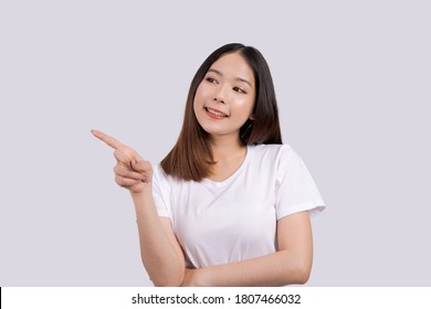 Young beautiful asian woman pointing to copy space, isolated on white background. - Shutterstock ID 1807466032