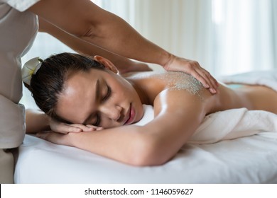 Young beautiful Asian woman relaxing in the spa massage and having salt scrub massage at back. healthy lifestyle and relaxation concept.