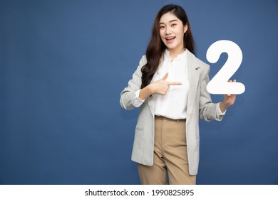 Young beautiful Asian woman showing number 2 and pointing up with finger number two isolated on blue background